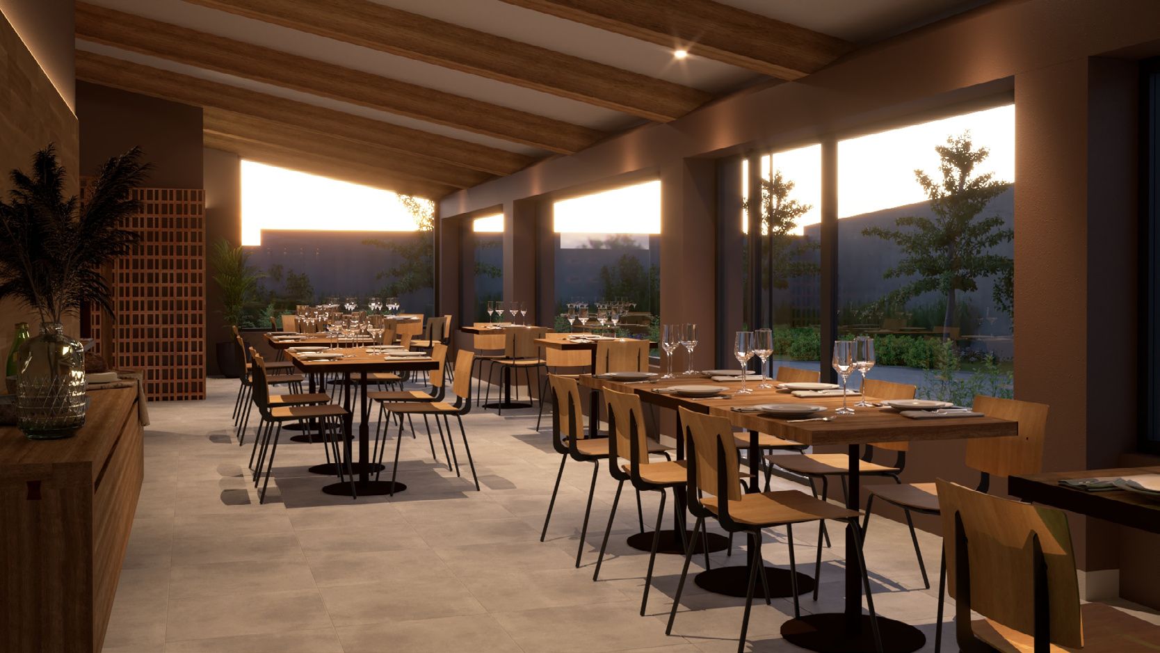 Terraza cubierta con mesas puestas al atardecer y ventanas abiertas al paisaje.